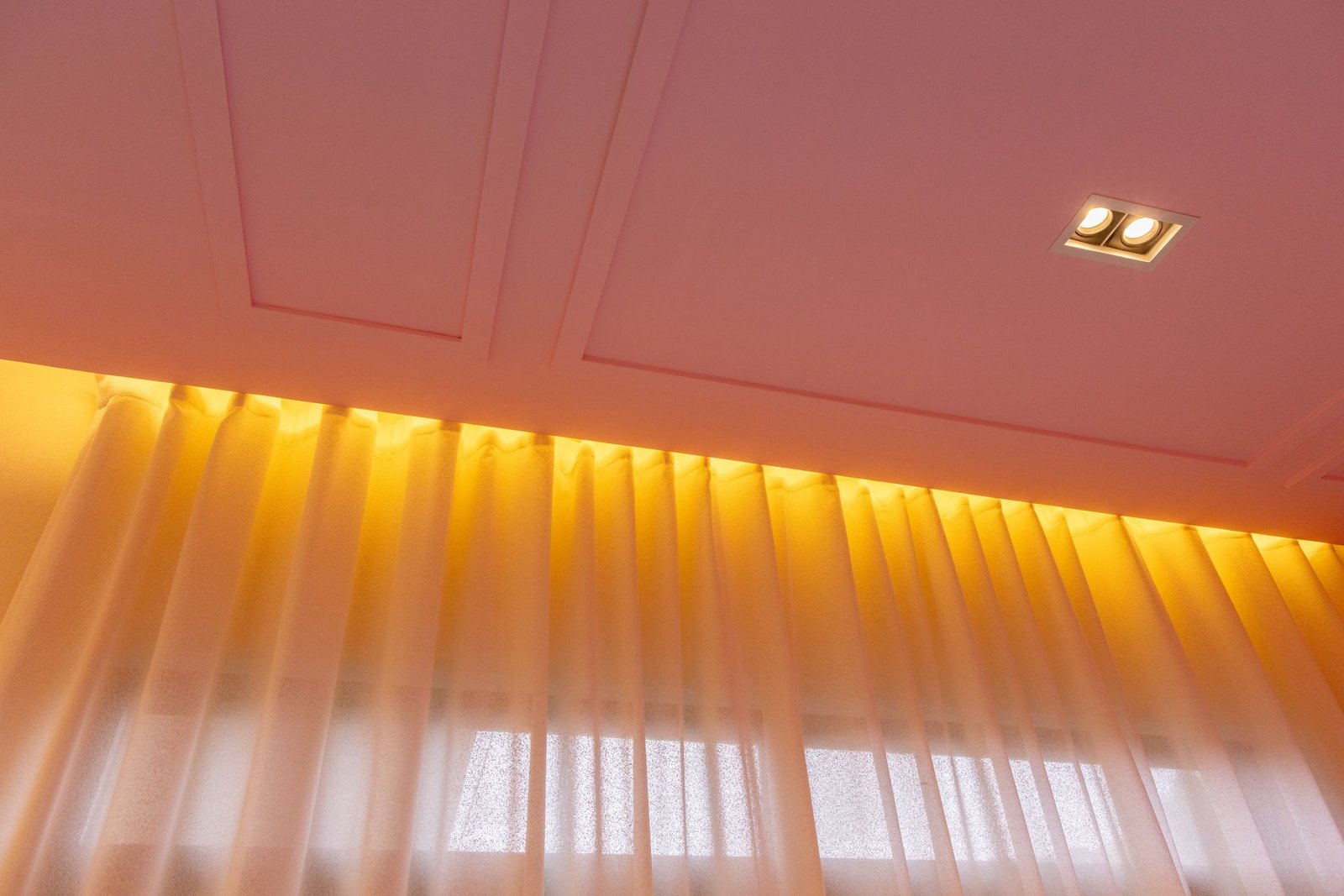 Visillo con iluminación cálida integrada bajo plafón, detalle de cortinas de Decora