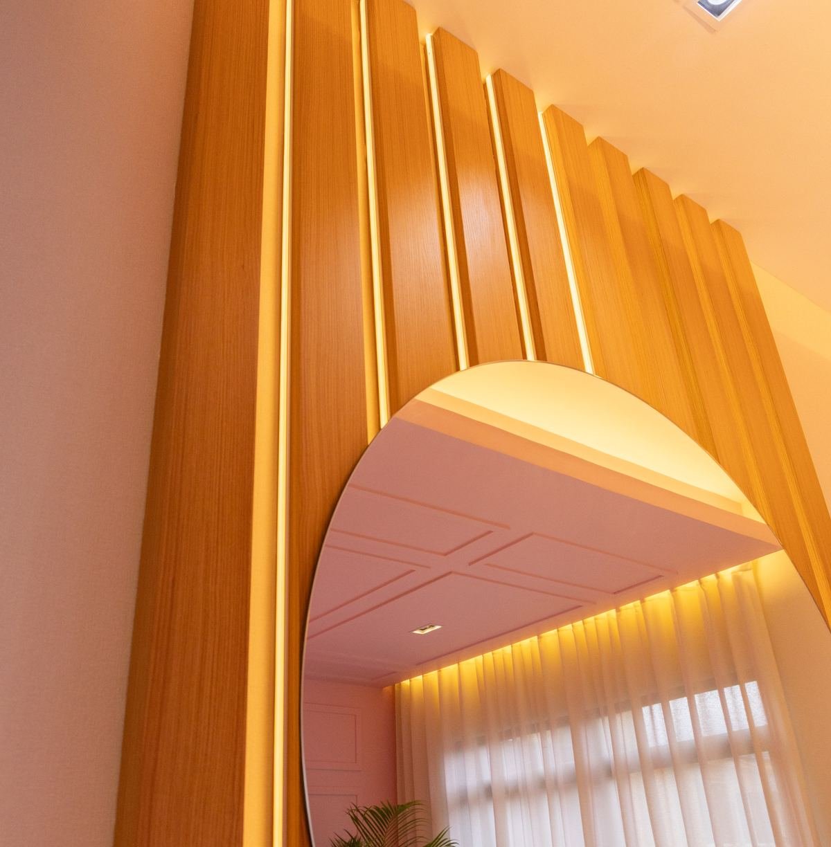 Espejo de arco sobre muro de listones de madera retroiluminados